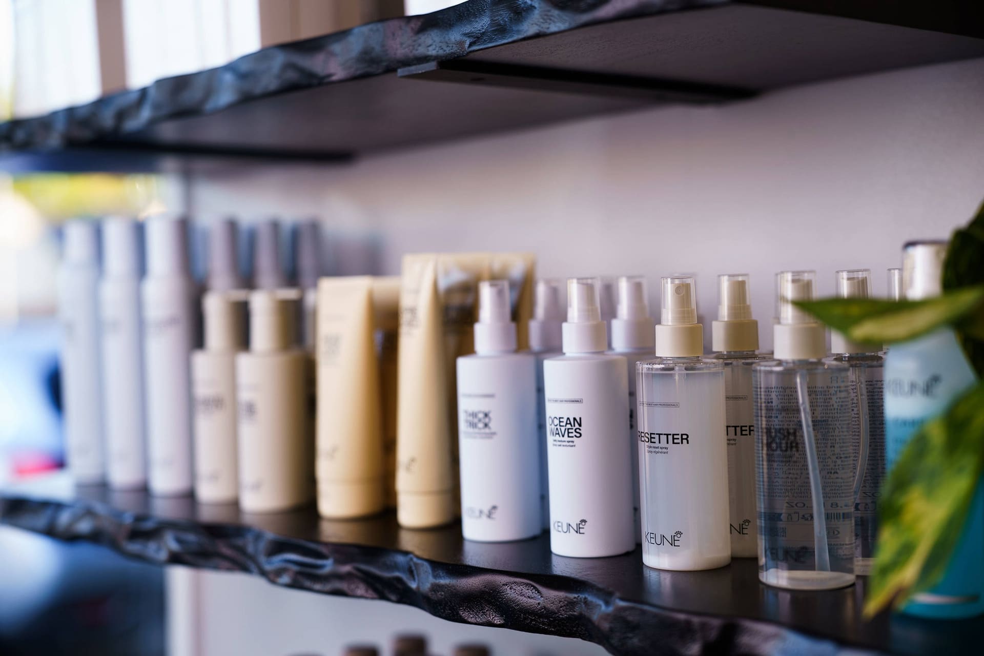 Keune styling products lined up on a black live-edge shelf